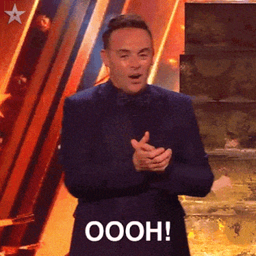 a man in a suit and bow tie is clapping and saying oooh !