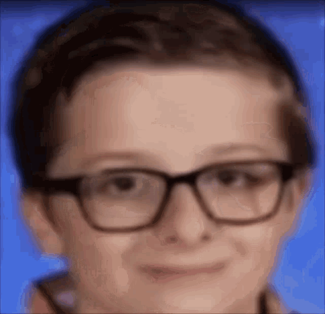 a close up of a boy wearing glasses and smiling .