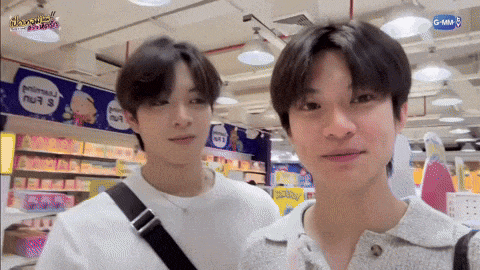 two young men are standing next to each other in a store looking at the camera .