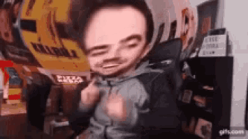a man with a small head is sitting in a chair making a face .
