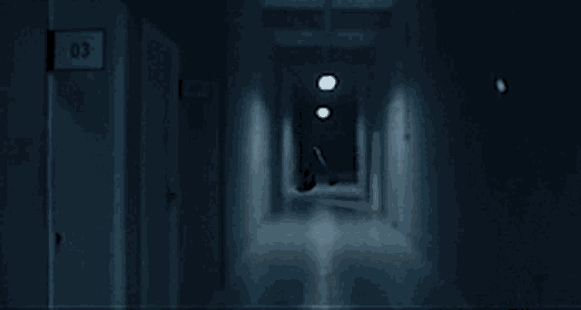 a scary woman is standing in a dark hallway .