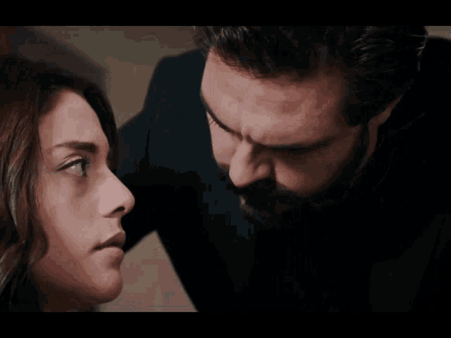 a man and a woman are looking at each other and the man has a beard