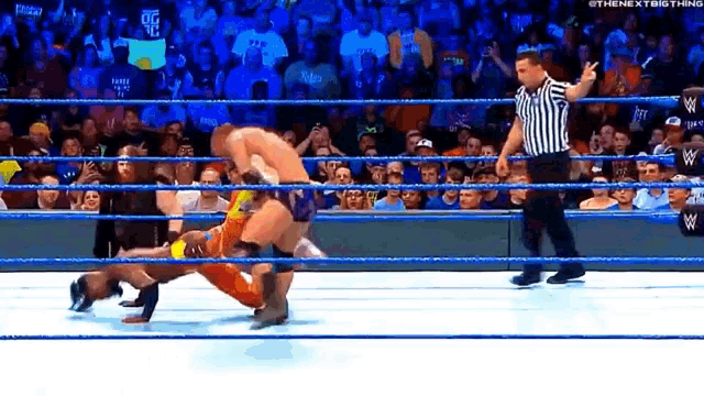 a referee is standing in the ring watching a wrestling match .