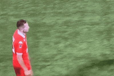a man in a suit is hugging a soccer player in a red jersey on a field .