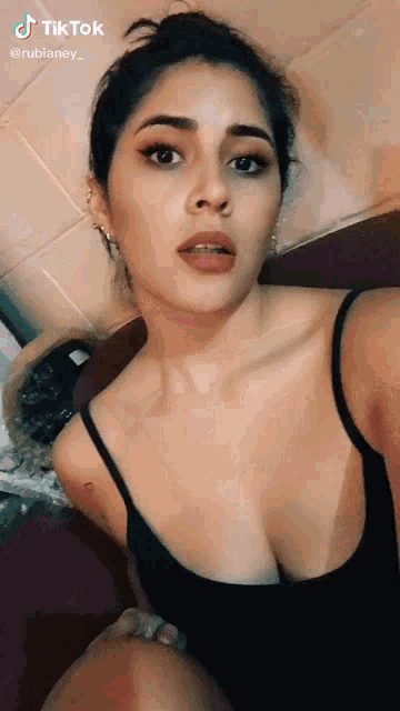 the woman is wearing a black tank top and taking a selfie .