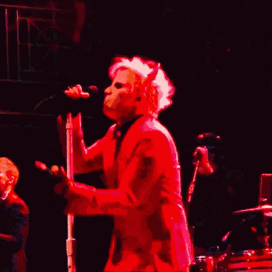 a woman in a red jacket is singing into a microphone on a stage