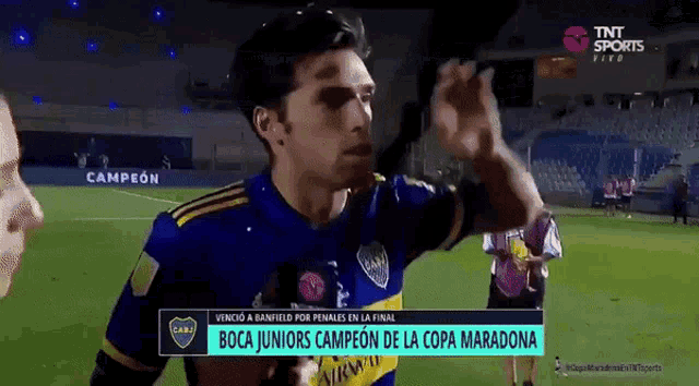 a man in a boca juniors jersey is giving a high five on a soccer field