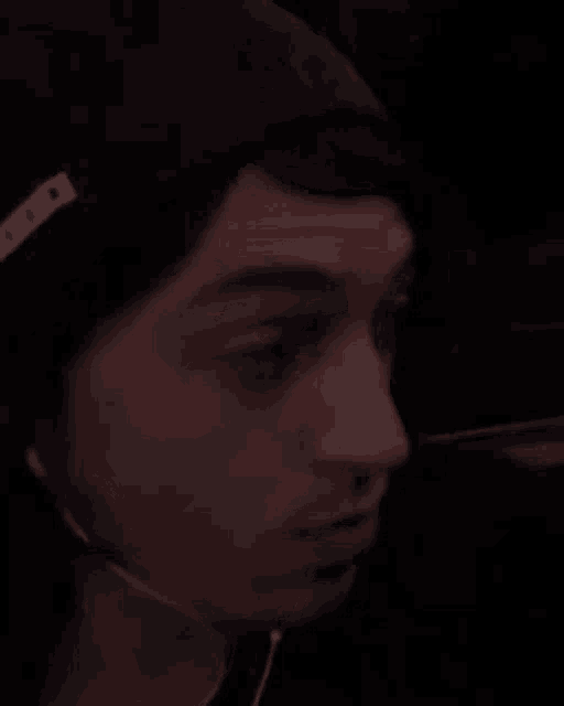 a man wearing a beanie and earbuds is making a funny face .