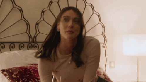 a woman laying on a bed with a fancy headboard