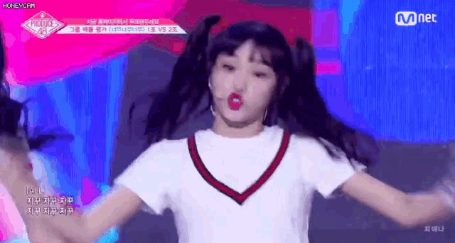 a girl in a white shirt and red sweater is dancing on a stage in front of a microphone .