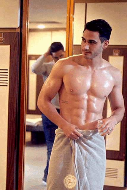 a shirtless man in a locker room with a towel around his waist that says abercrombie