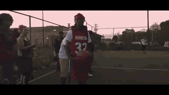 a man in a red jersey with the number 32 on it holds a basketball