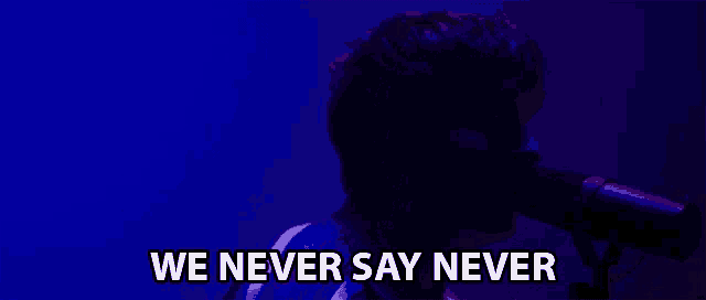 a man singing into a microphone with the words " we never say never " below him