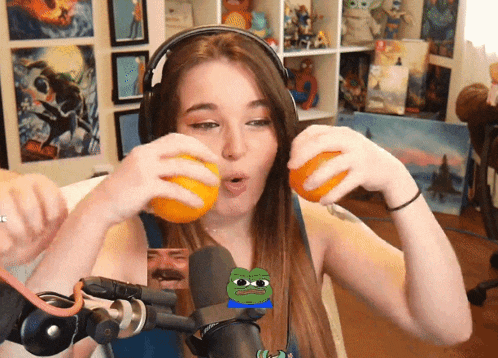 a girl wearing headphones is holding oranges in front of a microphone with a pepe face on it