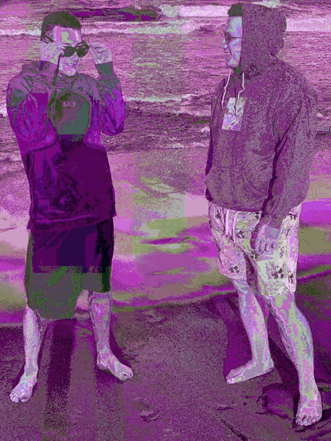 two men standing on a beach with one wearing a hoodie that says ' nike ' on it
