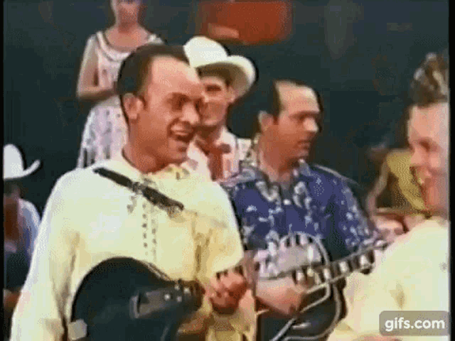 a man is playing a guitar and singing in front of a group of men .