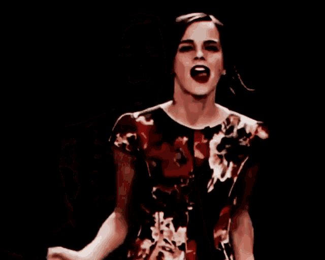 a woman in a red and black floral top is laughing with her arms outstretched