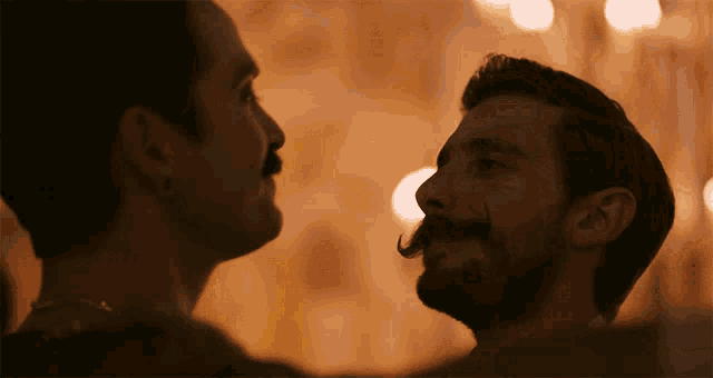 a man with a beard and mustache looks at another man