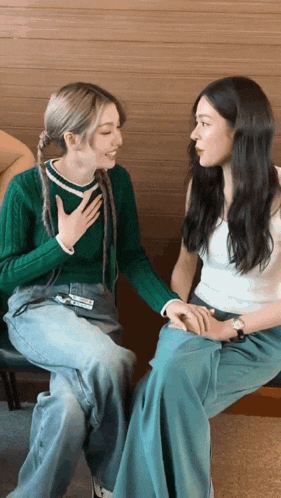 two women sitting next to each other with one wearing a green sweater