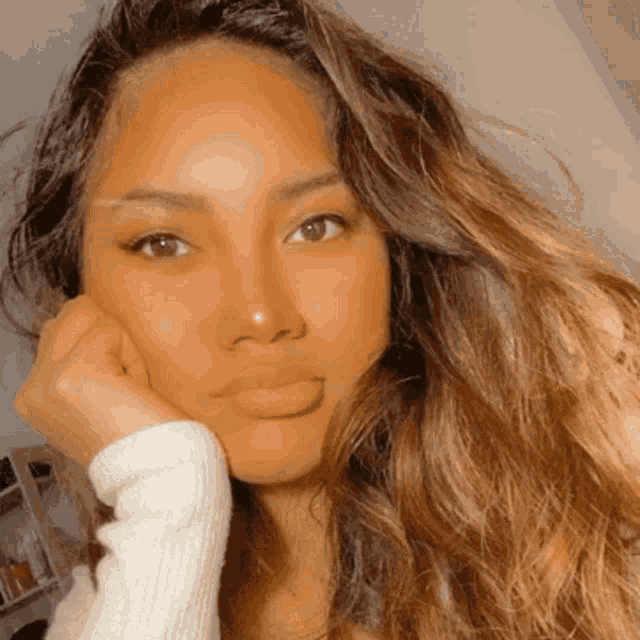 a close up of a woman 's face with a hand on her chin