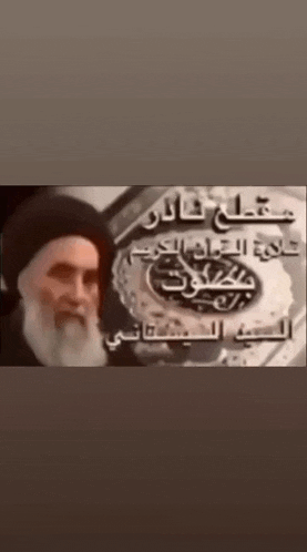 a man with a beard stands in front of a sign in arabic