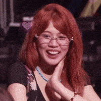 a woman with red hair is wearing glasses and a necklace and smiling .