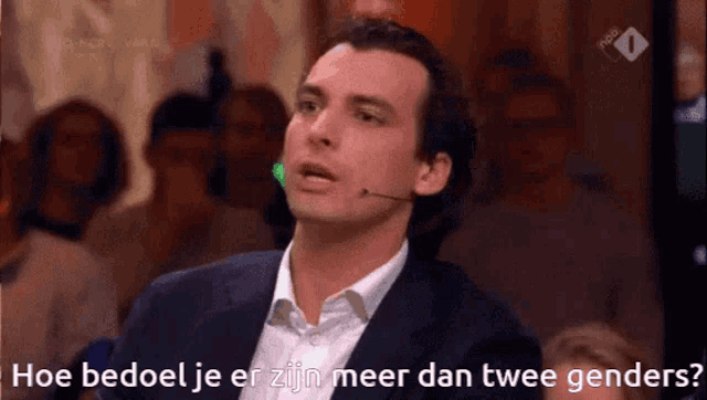 a man speaking into a microphone with the words hoe bedoel je er zijn meer dan twee genders behind him