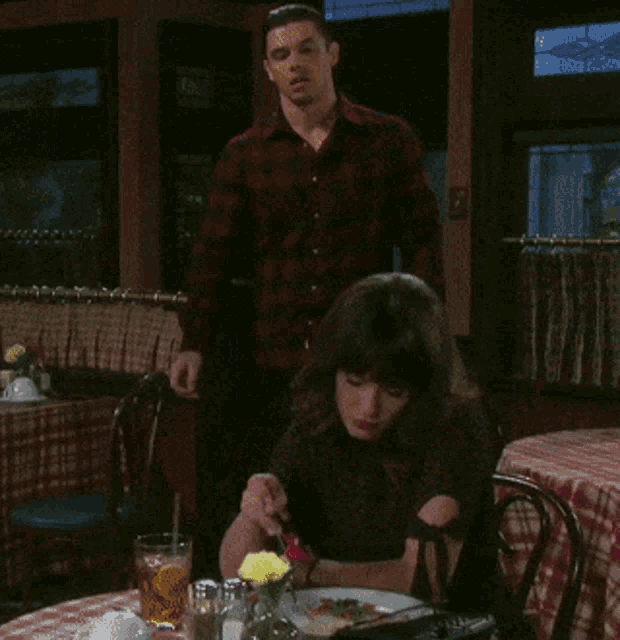 a man and a woman sit at a table with a plate of food