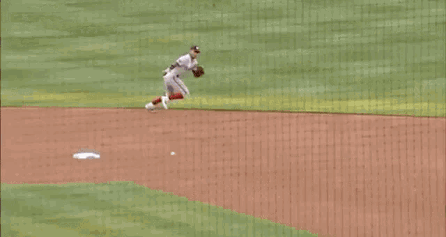 a baseball player is sliding into a base while trying to catch a ball .
