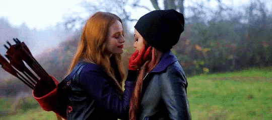 two women are standing next to each other in a field .