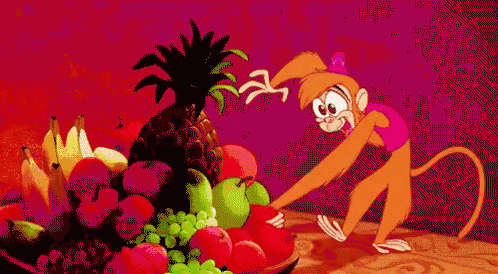 a monkey is standing next to a bowl of fruit on a table