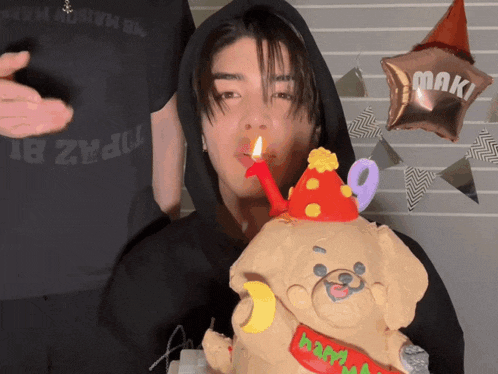 a man blowing out a candle next to a teddy bear wearing a party hat