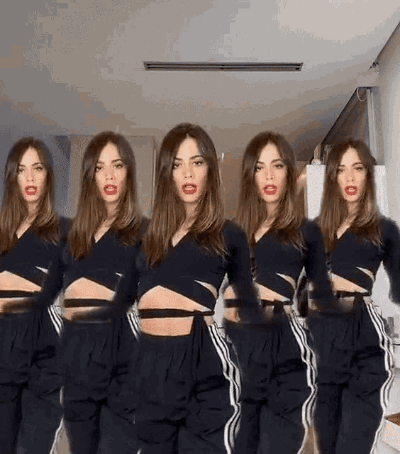 a woman in a black crop top and black pants is standing in a row