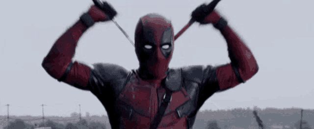 a man in a deadpool costume is holding a pair of swords
