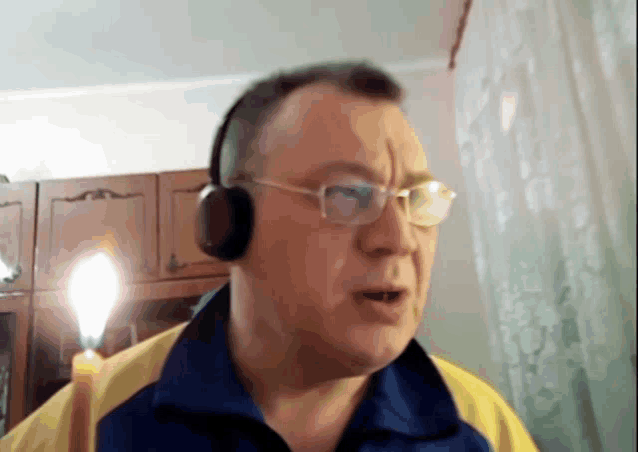 a man wearing headphones and glasses is standing in front of a candle