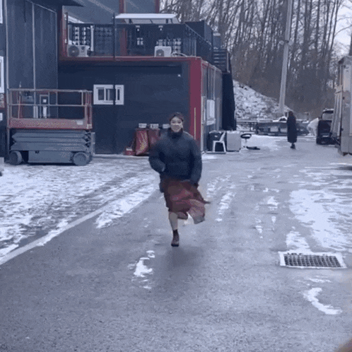 a woman in a skirt is running down a snowy road