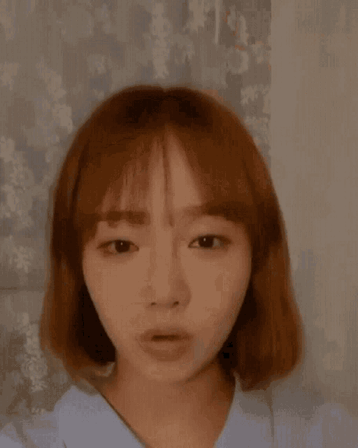 a close up of a woman 's face with her hand on her hair .