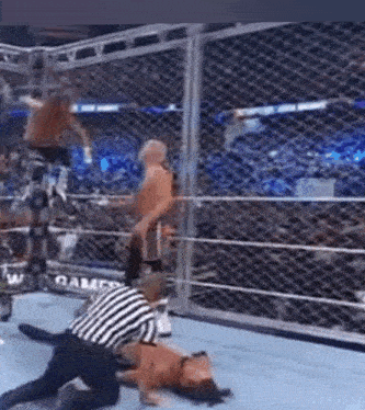a referee is kneeling down next to a wrestler in a wrestling ring during a match .