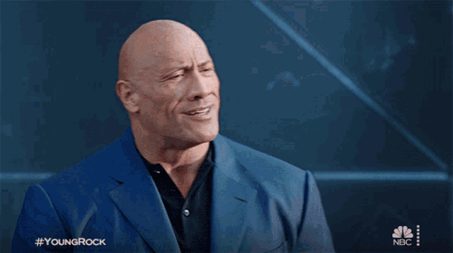 a bald man in a blue suit with the hashtag youngrock
