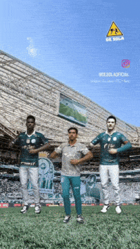 three soccer players are dancing in front of a stadium with a yellow warning sign above them that says de sola