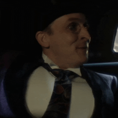 a man in a suit and tie is sitting in a car and smiling .