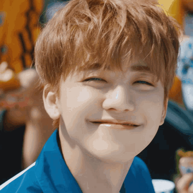a young man wearing a blue shirt is smiling