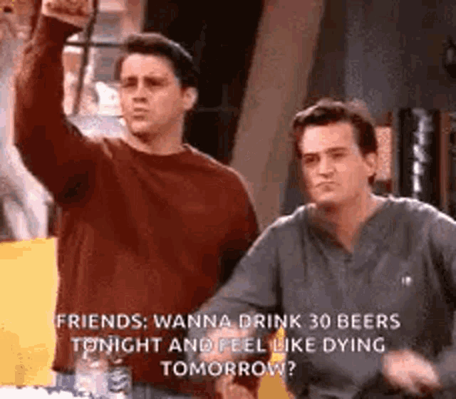 two men are standing next to each other and one is holding a beer .
