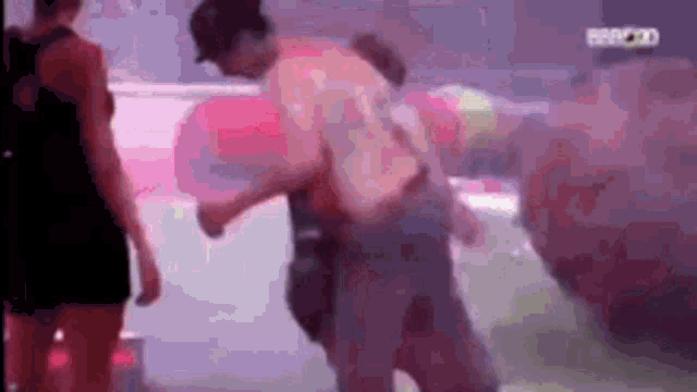 a man is holding another man in his arms while standing in front of a crowd .