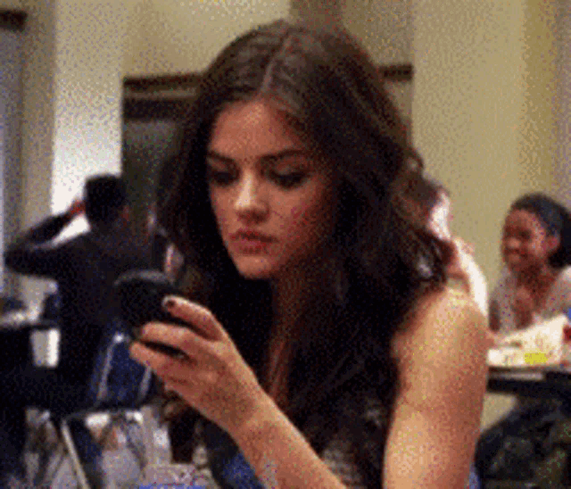 a woman is sitting at a table looking at her cell phone