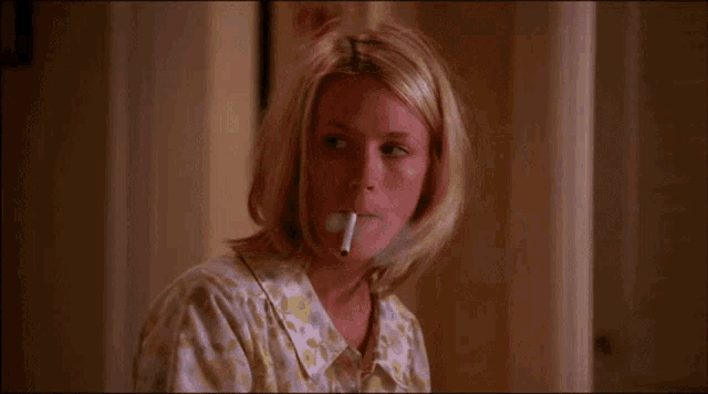 a woman with blonde hair is smoking a cigarette in a room