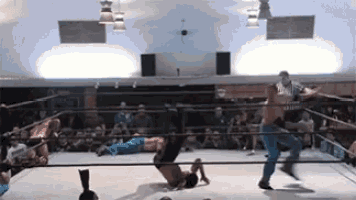 two men are wrestling in a wrestling ring while a referee watches .