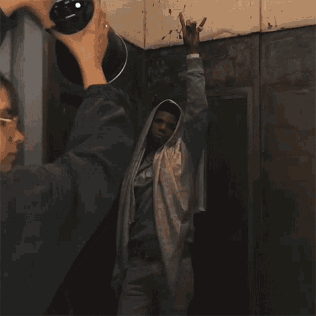 a man in a hoodie is being photographed by a camera