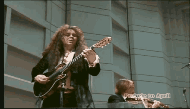 a man playing a guitar next to a woman playing a violin with the words " preview to april " on the bottom