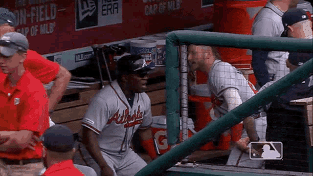 a baseball player wearing an atlanta jersey talks to another player